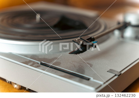 Close-up of a vintage turntable with a stylus arm positioned above a vinyl record, showcasing the intricate details of the audio equipment and its nostalgic charm Close-up of a vintage turntable with a stylus arm positioned above a vinyl record, showcasing the intricate details of the audio equipment and its nostalgic charm 132462230