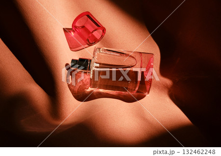 A pink perfume bottle on a soft reddish background. A pink perfume bottle on a soft reddish background. 132462248
