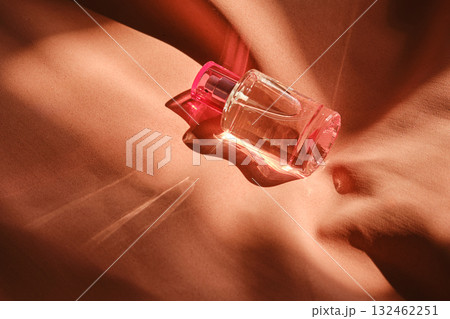A pink perfume bottle on a soft reddish background. 132462251