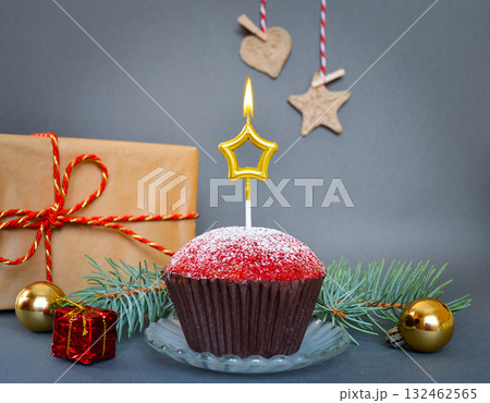 Christmas composition with a cupcake and a candle, on a gray background. 132462565