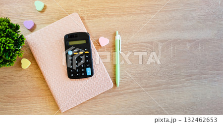 On the wooden surface of the table lies a notepad with a pen, calculator and erasers. 132462653