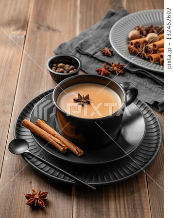 Traditional Indian masala chai tea with milk and spices in a black cup on a dark wooden background Traditional Indian masala chai tea with milk and spices in a black cup on a dark wooden background 132462692