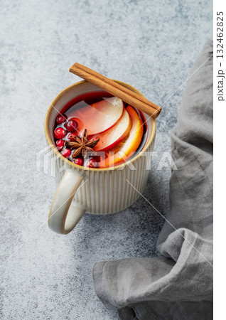 A hot cranberry Christmas drink with cinnamon in a mug on a gray background with napkin. 132462825