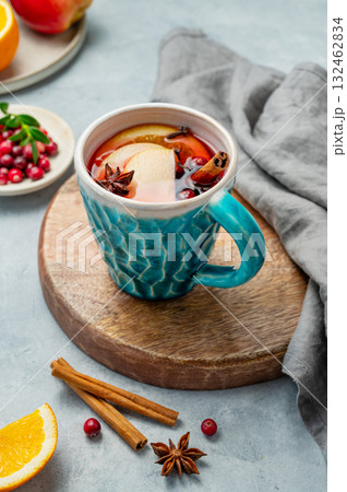 A mulled wine in a mug with cinnamon, cranberry and fruits on a wooden board on a light background A mulled wine in a mug with cinnamon, cranberry and fruits on a wooden board on a light background 132462834