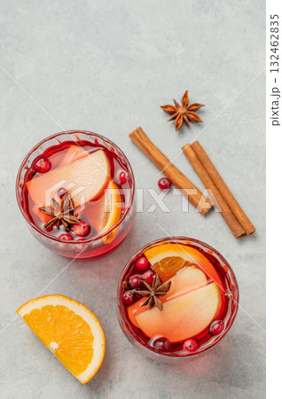 A cranberry drink in a glasses on a light background with cinnamon and citrus fruit. A cranberry drink in a glasses on a light background with cinnamon and citrus fruit. 132462835