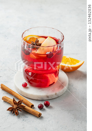 A cranberry drink in a glass on a light background with cinnamon and citrus fruit. A cranberry drink in a glass on a light background with cinnamon and citrus fruit. 132462836