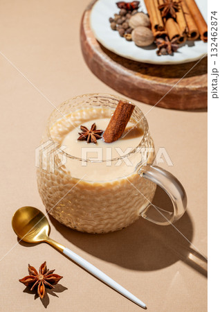 Traditional Indian masala chai tea with milk and spices in a cup on a beige background 132462874