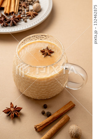 Traditional Indian masala chai tea with milk and spices in a cup on a beige background Traditional Indian masala chai tea with milk and spices in a cup on a beige background 132462875