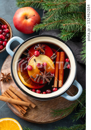 A pot of red mulled wine with spices, orange, apple slices, and cranberries on a dark background A pot of red mulled wine with spices, orange, apple slices, and cranberries on a dark background 132462884