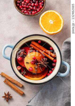 A pot of red mulled wine with spices, orange, apple slices, and cranberries on a light background 132462885