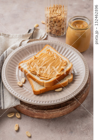 Peanut butter toast on a plate on a light background with scattered nuts, spread and napkin. 132462896