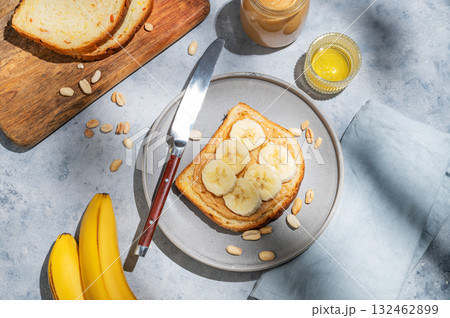Peanut butter toast with banana on a plate on a blue background with spread, bread, fruit, honey  132462899