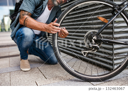 Man fixing bicycle wheel outdoors. 132463067