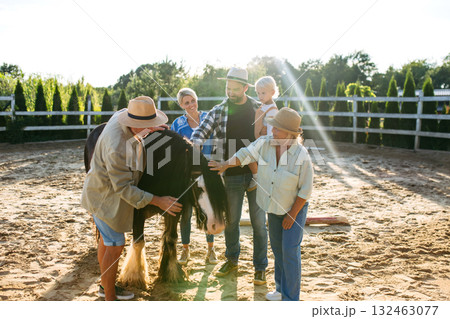Farmer family standing in horse paddock with pony. 132463077