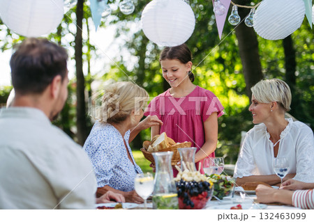 Family sharing food during garden grill party. 132463099