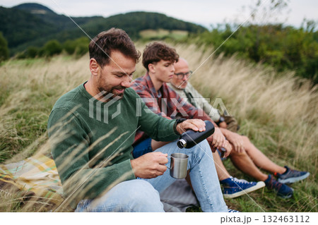 Grandfather, father and teen boy hiking togeter in nature, resting on meadow. Grandfather, father and teen boy hiking togeter in nature, resting on meadow. 132463112