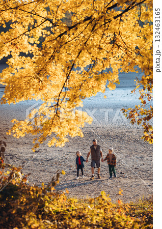Father holding hands with his two kids during fall walk. 132463165
