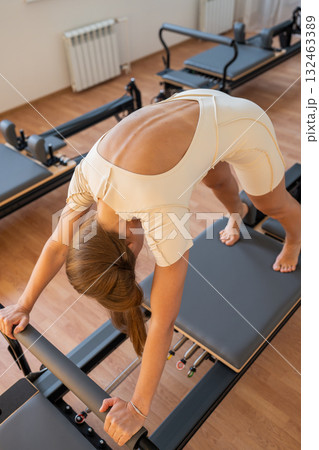 Pilates Woman showcases deep hamstring stretch, reformer exercise emphasizing hamstrings and breath control 132463389