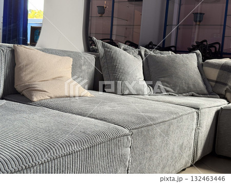 Modern gray corduroy sofa with cushions in bright living room. Comfortable home interior, cozy seating area and soft texture emphasizing relaxation and minimalism. Modern gray corduroy sofa with cushions in bright living room. Comfortable home interior, cozy seating area and soft texture emphasizing relaxation and minimalism. 132463446