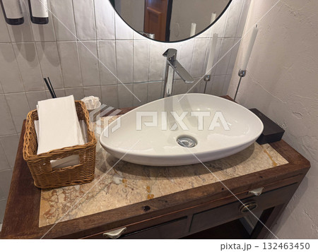 Stylish sink on wooden vanity in restroom interior. Cleanliness, design harmony, and comfort in modern hospitality environment. 132463450