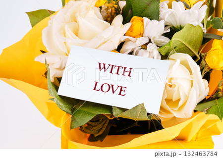 A vibrant arrangement of fresh flowers, including white roses and colorful blooms, is complemented by a note saying with love, conveying deep emotions and warmth A vibrant arrangement of fresh flowers, including white roses and colorful blooms, is complemented by a note saying with love, conveying deep emotions and warmth 132463784