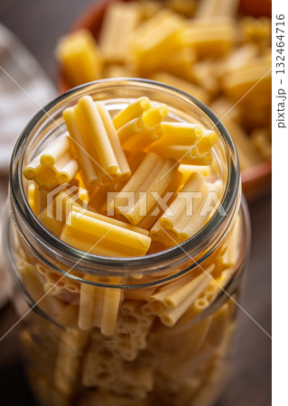 Cinque buchi. Uncooked italian pasta in jar on wooden table. 132464716