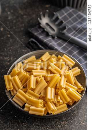 Cinque buchi. Uncooked italian pasta in bowl on black table. 132464726