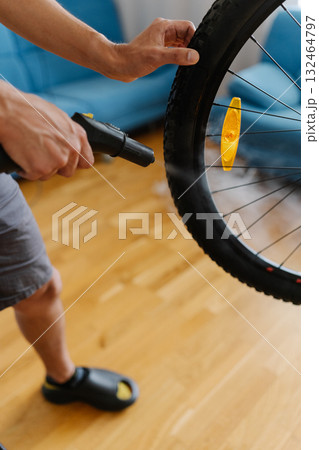 Owner bike cleaning dirty dusty tire of bicycle wheel using steam cleaner, ensuring thorough cleaning in home environment, close-up vertical cropped shot. Concept of bike maintenance, service. 132464797
