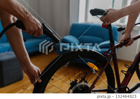 Cropped shot of two cyclists cleaning bicycle wheel using high-pressure steam cleaner, removing stubborn dirt at home, demonstrating meticulous bicycle maintenance technique. Concept of bike service Cropped shot of two cyclists cleaning bicycle wheel using high-pressure steam cleaner, removing stubborn dirt at home, demonstrating meticulous bicycle maintenance technique. Concept of bike service 132464823