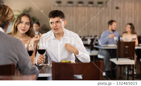 Couple and adult man eating and talking in restaurant Couple and adult man eating and talking in restaurant 132465015