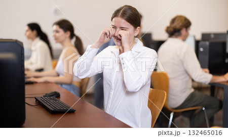 After working on computer, girl rubs tired eyes with fists After working on computer, girl rubs tired eyes with fists 132465016
