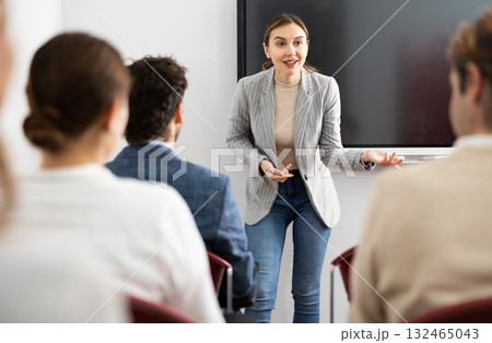 Young female professor explaining subject to classroom full of students 132465043