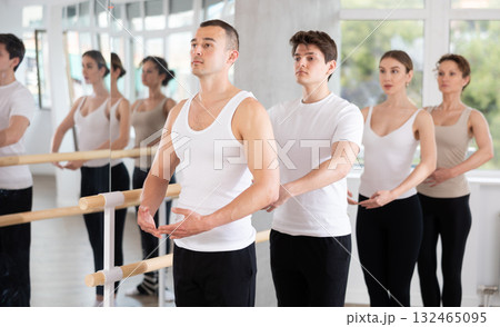 Man mastering first ballet position at barre at group class 132465095