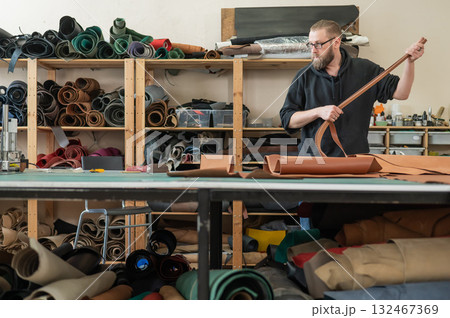 Caucasian bearded man working as a tanner in a workshop.  132467369
