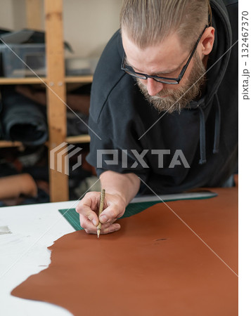 Caucasian bearded man working as a tanner in a workshop. Caucasian bearded man working as a tanner in a workshop. 132467370