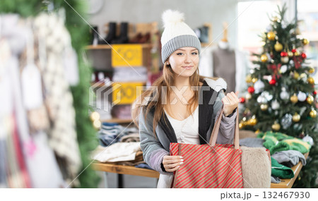 Girl customer inspects stores assortment, looks closely at warm wardrobe items 132467930