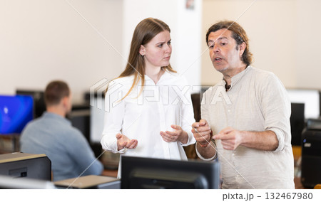 Male teacher helps girl with learning on computer in university computer class 132467980