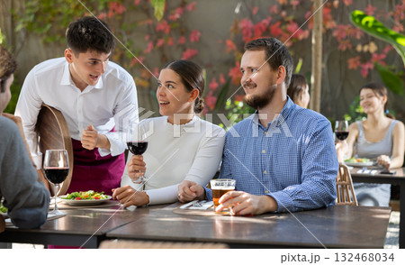 Waiter talking to restaurant guests - taking orders for food and drinks Waiter talking to restaurant guests - taking orders for food and drinks 132468034