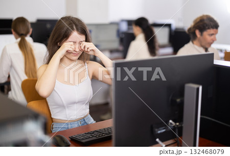 After working on computer, girl rubs tired eyes with fists After working on computer, girl rubs tired eyes with fists 132468079