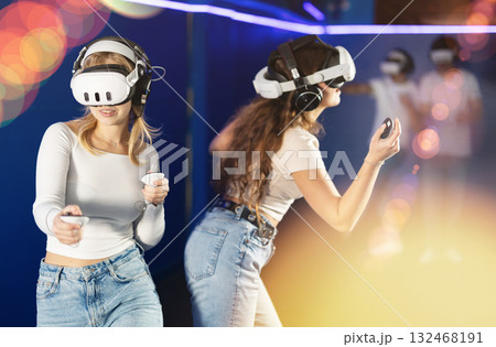 Two girls wearing virtual reality glasses participate in game with opponents Two girls wearing virtual reality glasses participate in game with opponents 132468191