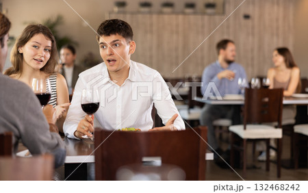 Couple and adult man eating and talking in restaurant Couple and adult man eating and talking in restaurant 132468242