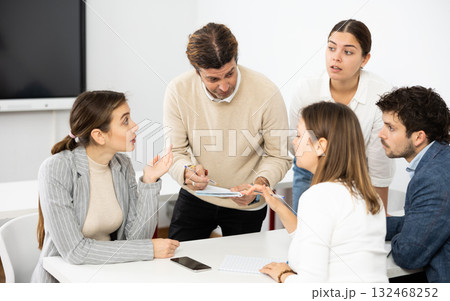 Emotional language teacher telling interesting stories to adult attentive students during class break in auditory Emotional language teacher telling interesting stories to adult attentive students during class break in auditory 132468252