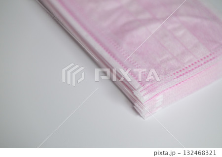 積み重ねられた淡いピンク色の不織布マスク 132468321