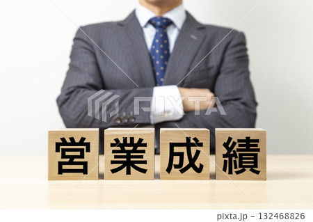 「営業成績」と書かれたブロックと腕組みをするビジネスマン 「営業成績」と書かれたブロックと腕組みをするビジネスマン 132468826