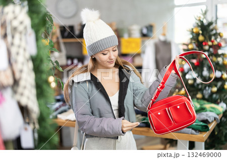 Girl client looks at products in store, looks closely at bag, picks up wardrobe item Girl client looks at products in store, looks closely at bag, picks up wardrobe item 132469000
