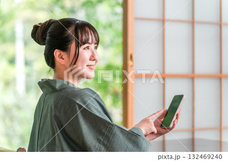 旅館の和室でスマホを見る浴衣姿の女性 旅館の和室でスマホを見る浴衣姿の女性 132469240