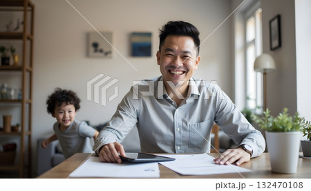 Joyful Father Working at Home with Child Playing in Background During Daytime Joyful Father Working at Home with Child Playing in Background During Daytime 132470108
