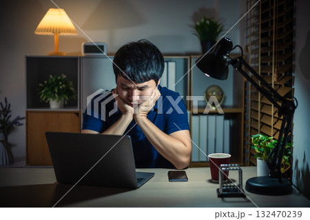 worried man working with laptop at night 132470239