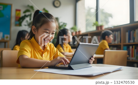 Happy Child Engaged in Learning with Tablet in Bright Classroom Environment 132470530