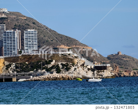 tranquil seaside scene with vibrant colors, peaceful waters meet lively urban cliff backdrop 132471803